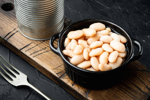 istock White canned beans, with metal can, in bowl, on black stone background 1320134698
