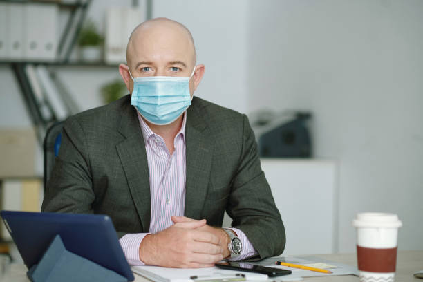 istock Mature bald businessman sitting at desk 1320135641