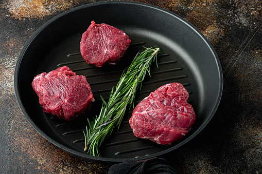 Raw meat beef steak. Black angus prime meat  set, Filet mignon tenderloin cut, in cast iron frying pan, on old dark rustic background