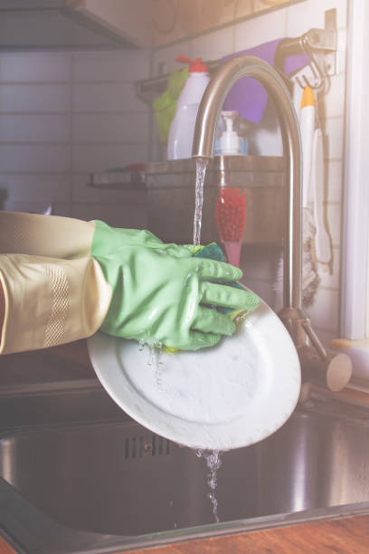 istock Dish washer with green rubber gloves. Close-up. 1320136271