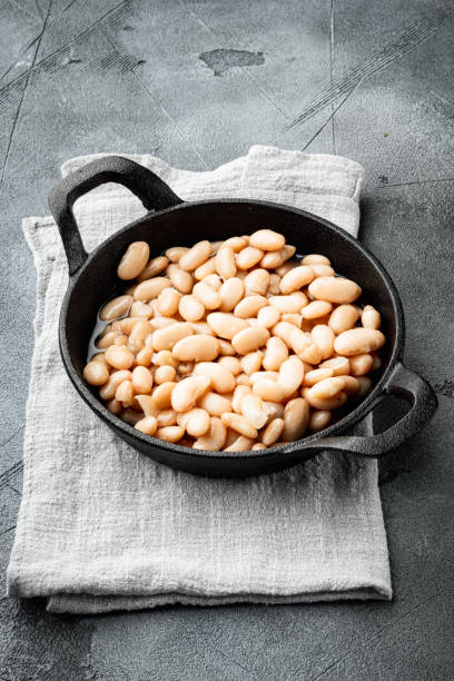 istock Canned white beans, in cast iron frying pan, on gray stone background 1320136736