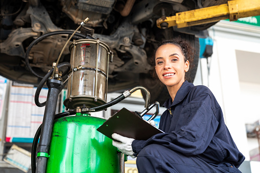 Auto services and Car repairs. A car mechanic is changing the oil in a car repair workshop.