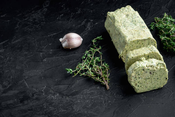 istock Dairy green butter with herbs, on black stone background, with copy space for text 1320138400