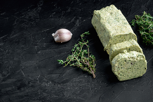 Dairy green butter with herbs set, on black stone background, with copy space for text