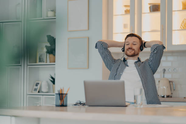 istock Smiling man holding hands behind head and relaxing while working online 1320138758