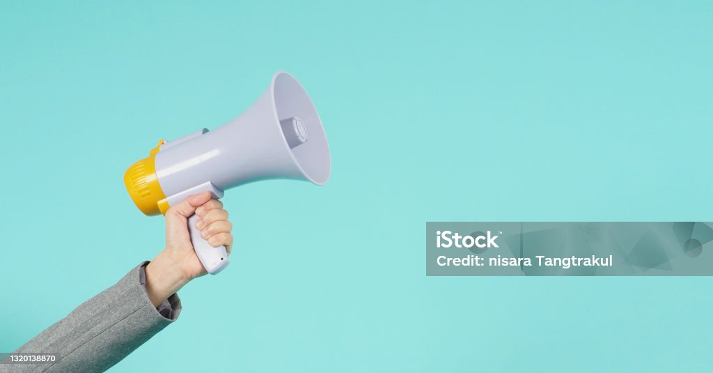 Hand is hold megaphone and wear grey suit on green or mint or Tiffany Blue background. Megaphone Stock Photo