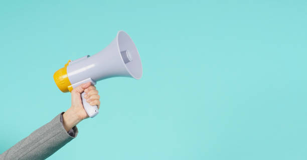 Hand is hold megaphone and wear grey suit on green or mint or Tiffany Blue  background. Hand is hold megaphone and wear grey suit on green or mint or Tiffany Blue  background. loudspeaker stock pictures, royalty-free photos & images