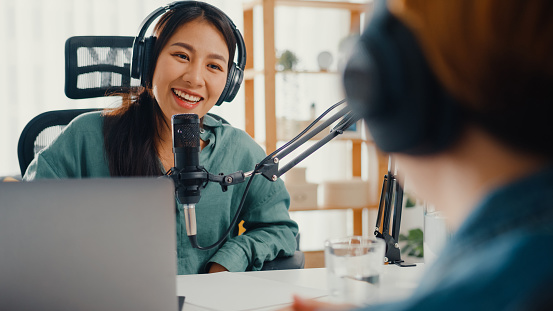 Asia chica presentadora de radio grabar podcast uso micrófono usar auriculares entrevista celebridad contenido invitado conversación hablar y escuchar en su habitación. photo