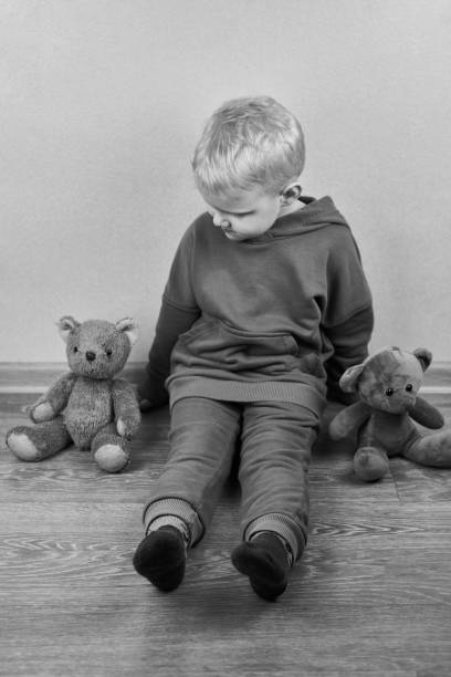 istock A three-year-old caucasian boy sits alone on the floor next to teddy bears. 1320141014