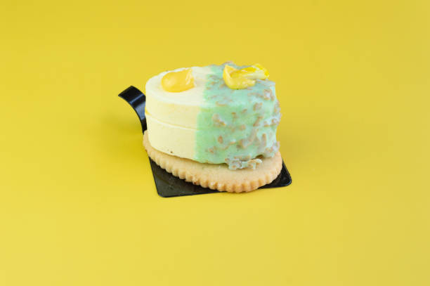 very elegant lemon and white chocolate dessert served with lemon zest on top over a sweet cookie on a yellow background