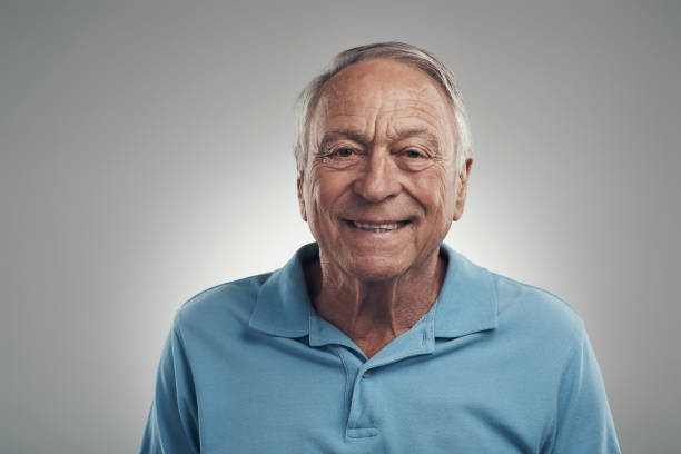 projectile d’un homme souriant heureusement à l’appareil-photo dans un studio sur un fond gris - model70 photos et images de collection