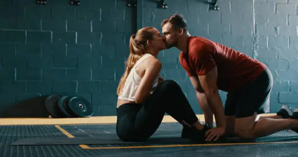 Photo of Shot of a man kissing his girlfriend while she does sit-ups