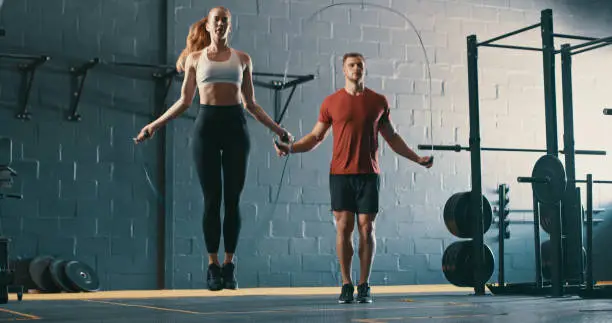 Photo of Shot of two young people working out with skipping ropes at the gym