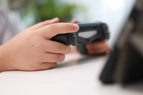 Close up of a young Asian boy playing video game with a game controller at home