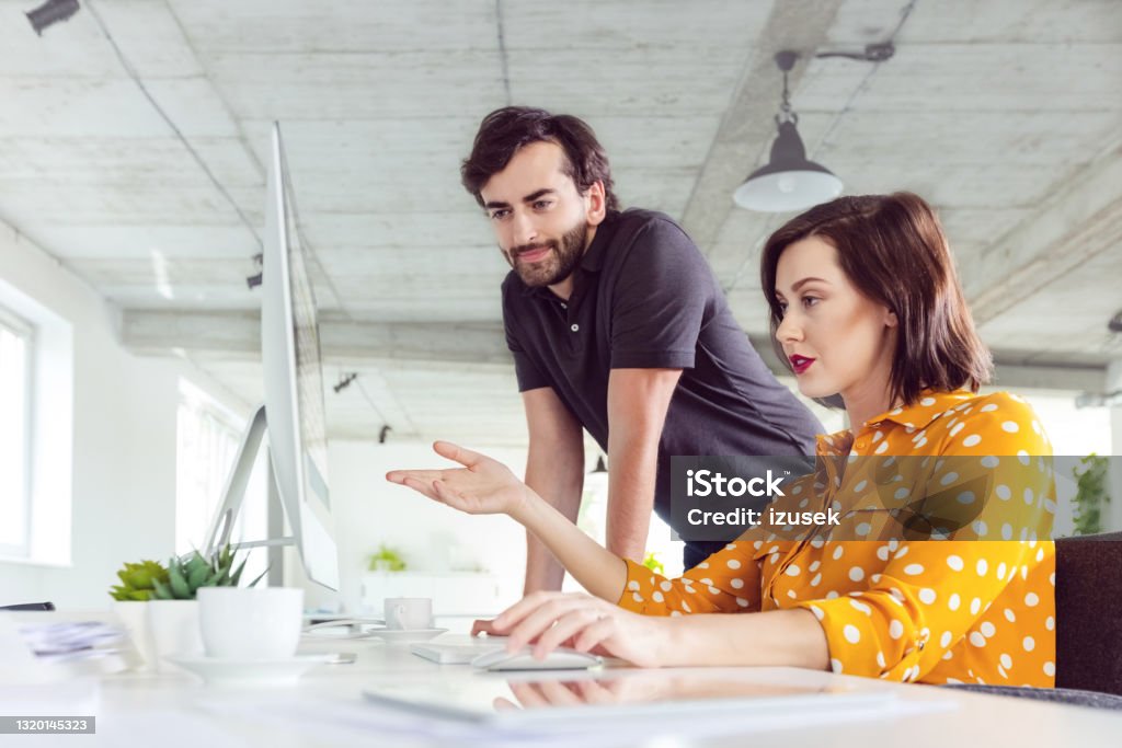 Coworkers in the office Mid adult man and women working together in the modern white office, discussing project on computer screen. Men Stock Photo
