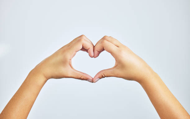 Cropped shot of an unrecognizable woman forming a heart shape with her hands. All you need is love heart hands multicultural women stock pictures, royalty-free photos & images