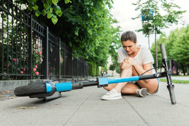 Young woman suffering from knee pain after e-scooter riding accident