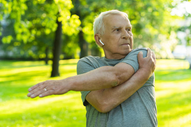 älterer mann trainiert im grünen stadtpark während seines fitnesstrainings - aging process morning outdoors horizontal stock-fotos und bilder