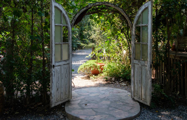 The large rustic wooden door on the stone pathway for partition the eatery zone and garden zone in the countryside coffee cafe, front view for the copy space.
