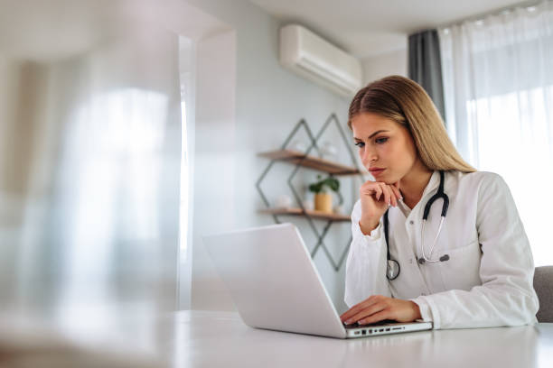 istock Blonde doctor at workplace, working over laptop. 1320151256