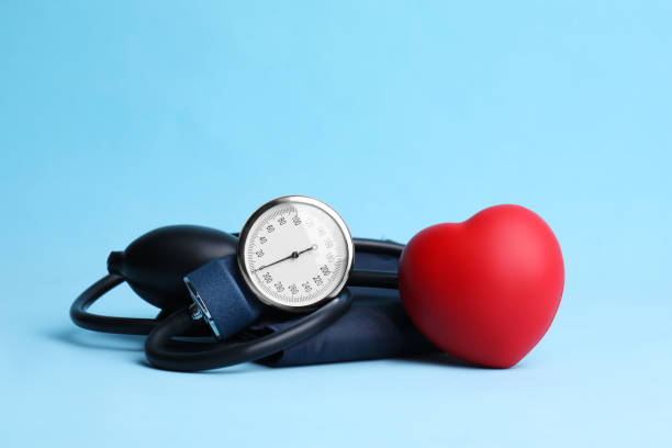 misuratore di pressione sanguigna e cuore giocattolo su sfondo azzurro - indicatore di pressione sanguigna foto e immagini stock