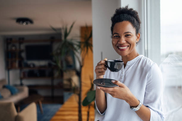 istock Smiling face, black woman, drinking tea at home. 1320153848