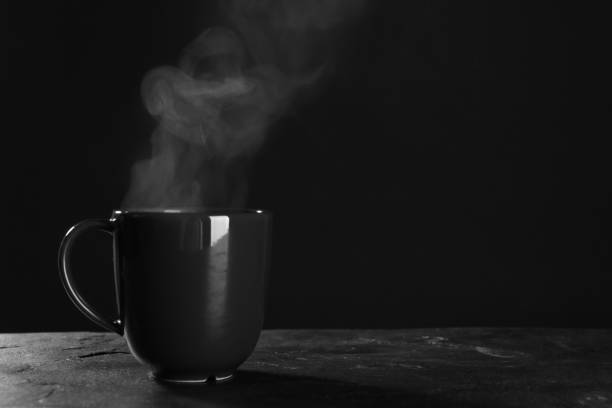istock Cup with steam on table against black background. Space for text 1320154102