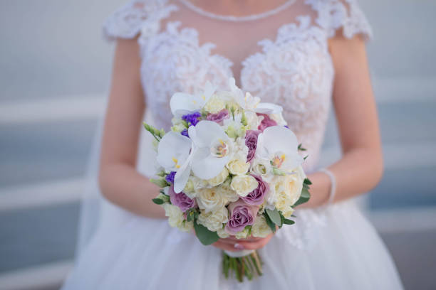 istock Beautiful Caucasian bride wearing an elegant white gown while holding a large bouquet 1320155879
