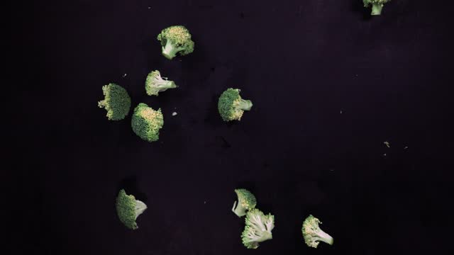 Broccoli falling on Black Surface and Slices
