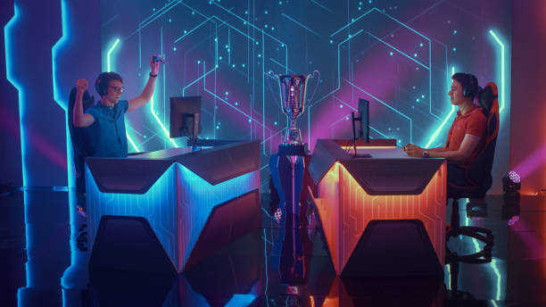 istock Two Professional Esport Gamers Using Controllers Playing Console Video Games on a Championship Event, One Player Celebrates Victory with Raised Hands. Global Online Streaming Cyber Gaming Tournament 1320158013