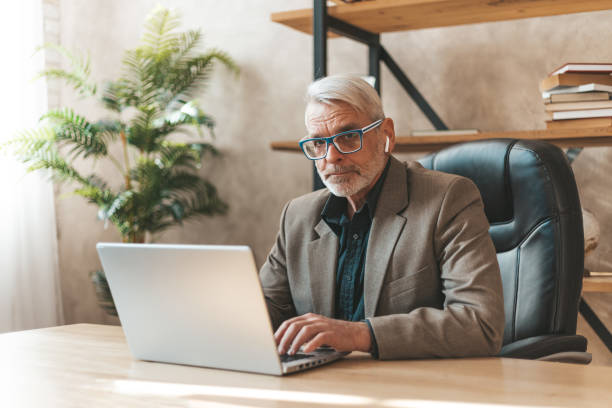 istock Experienced worker. Senior man at the workplace behind a laptop in the office. Analysis and search for information 1320160399