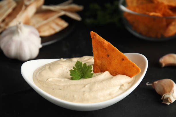 istock Delicious hummus with nacho chip and parsley on black table, closeup 1320161226