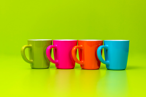 Multicolored coffee or tea cup on greeen background