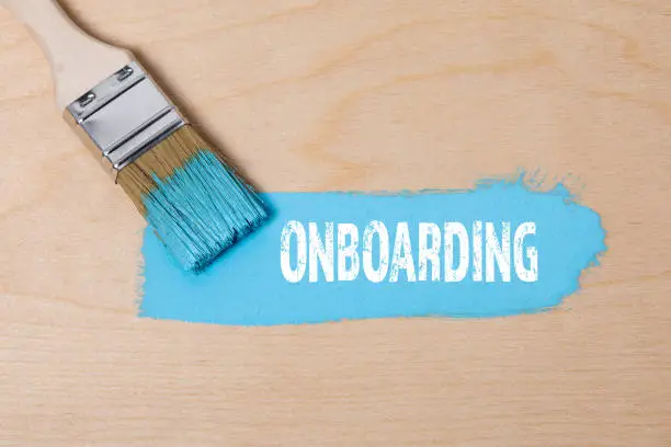Photo of ONBOARDING. Paint brush with blue paint on a wooden surface