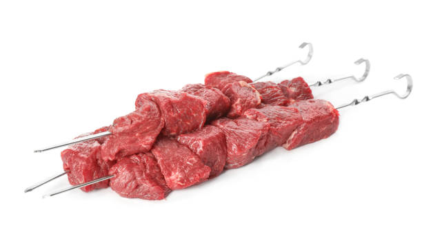 istock Metal skewers with raw meat on white background 1320162928