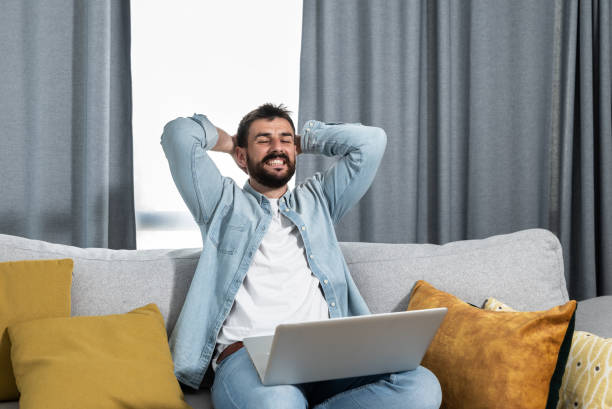 istock Young business freelancer man has finally completed a successful project for a foreign company and can now relax and enjoy the money he earned working from home on his laptop computer 1320166675