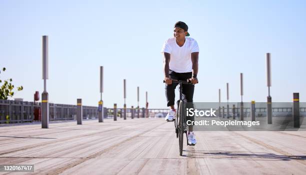 Shot Of A Young Man Riding A Bike On A Sunny Day Stock Photo - Download Image Now - Men, Real People, Fashionable