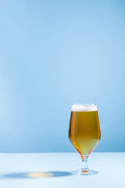 istock Refreshing beer in a glass on a blue background with a hard shadow. Copy space. 1320170371