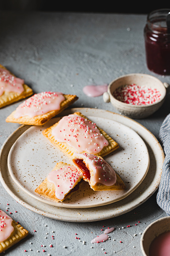 Pop tarts in a plate on gray table. Delicious and sweet toaster pastry with icing and sugar sprinkles.