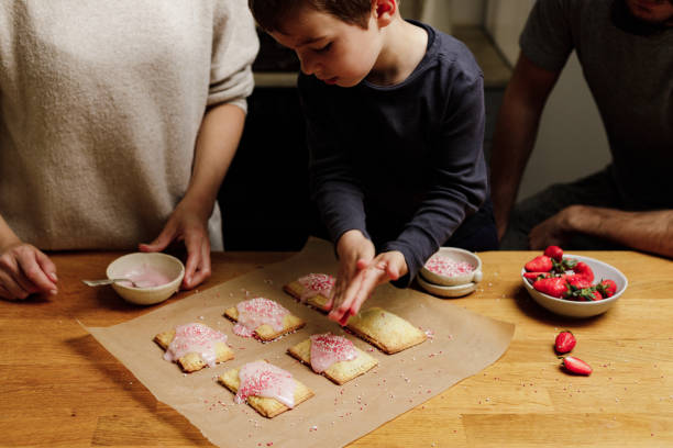 niño adornando tartas pop con espolvoreados de azúcar - family germany baking berlin germany fotografías e imágenes de stock