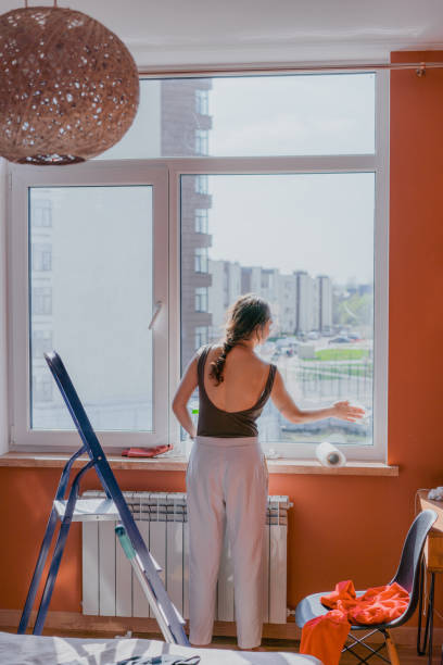 istock Woman cleaning window in apartment 1320172003