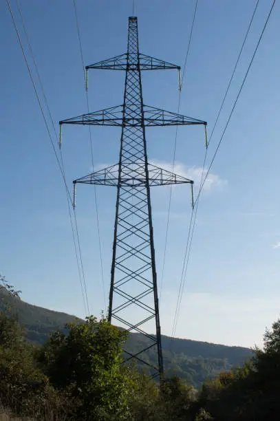 Transmission tower of high voltage overhead power lines in the middle of forest, in Croatia