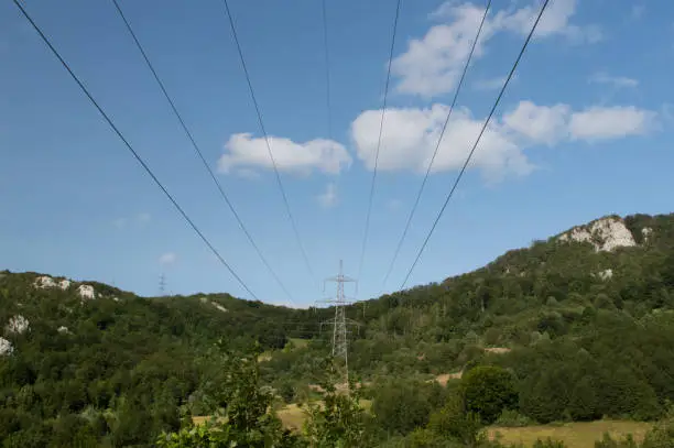 Transmission tower of high voltage overhead power lines in the middle of dense forest, visual pollution, in Ucka, Croatia