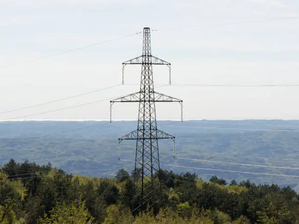 Transmission tower of high voltage overhead power lines in the middle of forest, in Croatia
