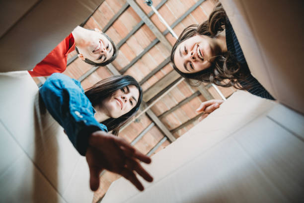 Three women are taking something from a cardboard box - View from inside the box