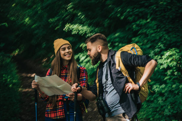istock Couple of hikers using trekking poles and a map while wearing backpacks 1320182143