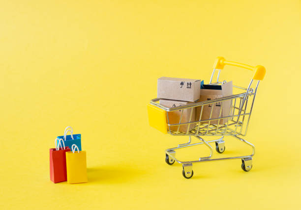 istock A small grocery cart with boxes and bags on a yellow background. 1320183081