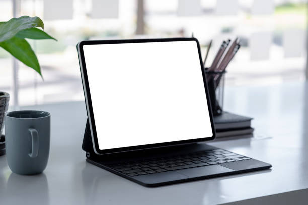 istock Tablet blank screen and a blank cup of coffee on the table at the office. Mock up. 1320185397