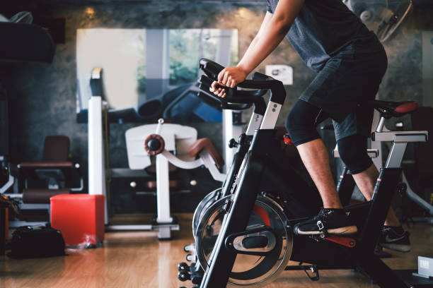 hombre hacer ejercicio en bicicleta en el gimnasio, hacer sus muslos fuertes y saludables. - bicicleta estática fotografías e imágenes de stock