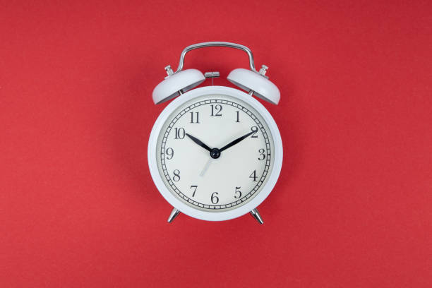 istock Retro alarm clock on red background. Old fashioned alarm clock 1320186303